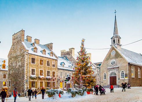 Quebec, Сanada- December 22, 2016: Winter day in the Petit Champlain neighborhood in Quebec City, Canada.\u2028Tourists stroll the streets of the neighborhood. The lights and festive garlands illuminate the place. Winter day in the Petit Champlain neighborhood in Quebec City, Canada.
