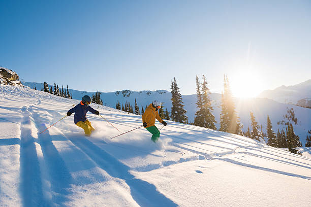 casal esquiando em um dia ensolarado de pó - skiing winter sport powder snow athlete - fotografias e filmes do acervo
