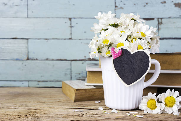 istock Daisy flowers in white cup with blank wood heart 636444922