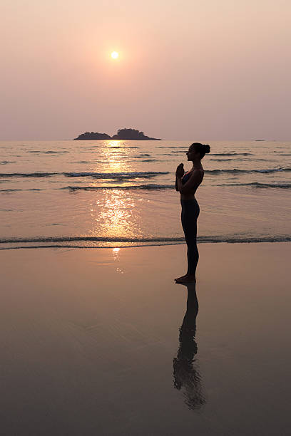 istock Young slim woman practicing pose from yoga on sunset beach 636448560