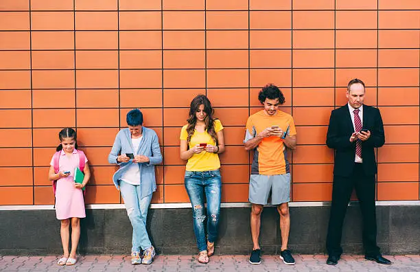 Five people at different ages texting seperately.