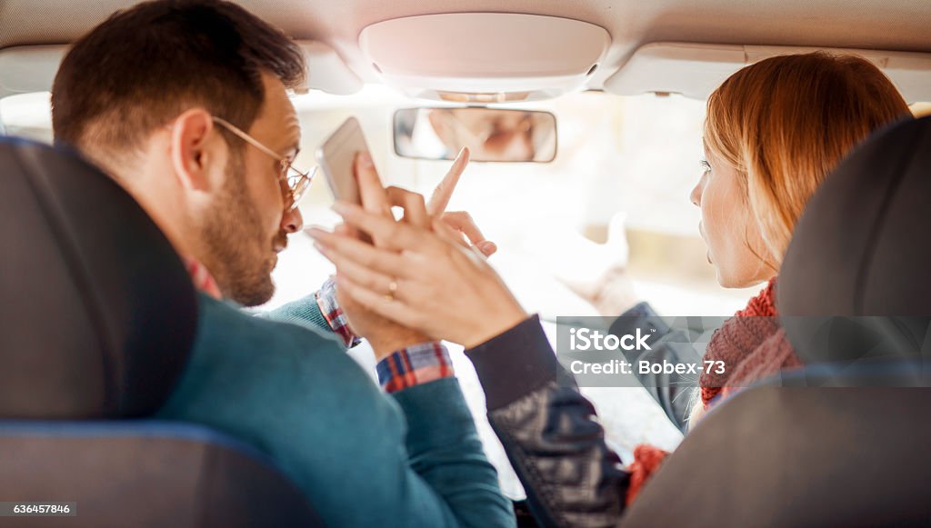 Dangerous driving and using a mobile phone Young woman showing a road in front of the car while the driver using a mobile phone and losing concentration. Dangerous driving Car Stock Photo