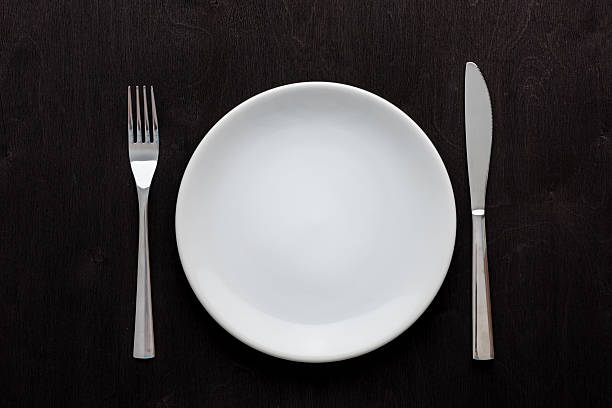 istock white plate on black wooden table 636463914