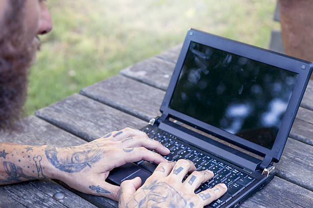 istock hands of a tattooted man working with computer outdoor 636464312