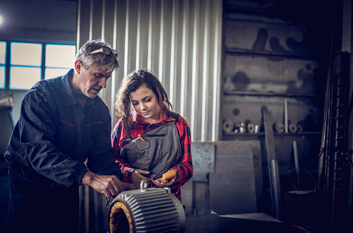 Senior man and young girl working in a workshop together.