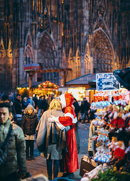 Woman taking photograph with Santa during Christmas Market Strasbourg, France - December 20, 2016: Woman taking photograph with Santa during Christmas Market in front of the Cathedral Notre-Dame in Strasbourg, Alsace notre dame de strasbourg stock pictures, royalty-free photos & images