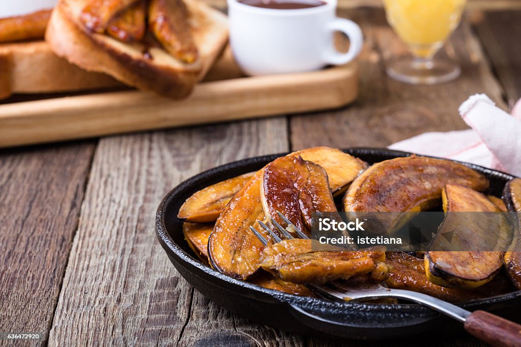 Homemade caramelised banana, vegan dessert Homemade caramelised banana in  cast iron frying pan on wooden rustic pan, vegan dessert Banana Stock Photo