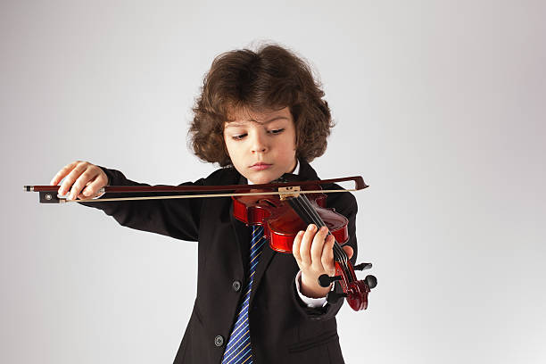 istock Beautiful cute young boy playing the violin. Gray background. 636477266