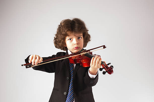 istock Handsome cute young boy playing the violin, looking at camera 636477300