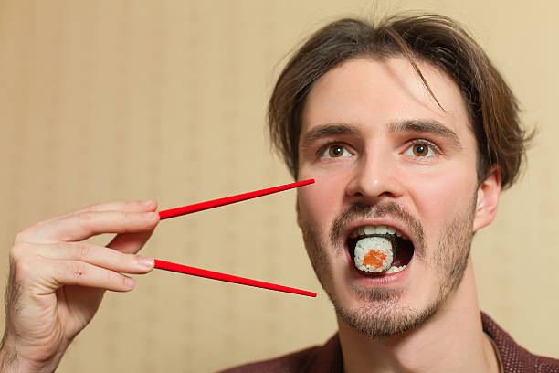 Businessman eat sushi with chopsticks.