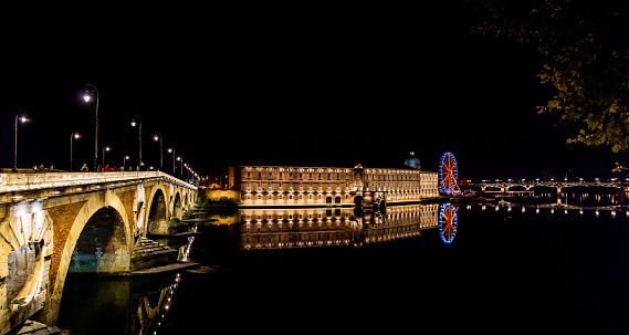 Pont Neuf bridge, the Hôtel-Dieu Saint-Jacques hospital and Ferris wheel at night in Toulouse.