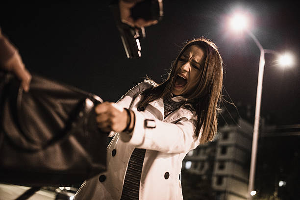 Woman in danger Robber stealing businesswoman purse in the middle of the street at night. Robber is pointing a gun at her. man holding gun at night in the city stock pictures, royalty-free photos & images