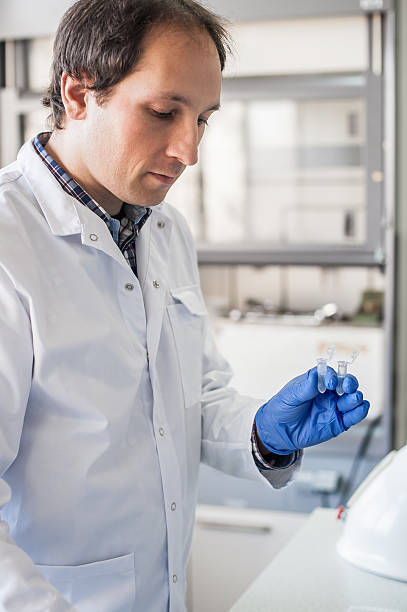 istock Male lab technician holding a test tube with sample 636481224