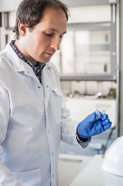 Photo of Male lab technician holding a test tube with sample