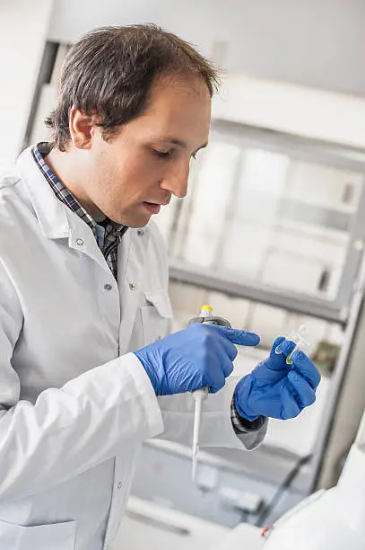 Photo of Male lab technician holding a test tube with sample