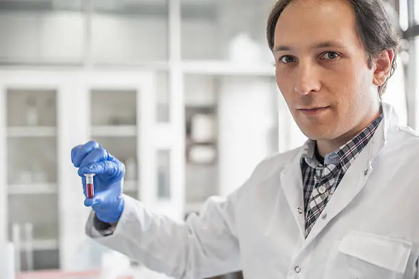 Photo of Male lab technician holding a test tube with sample