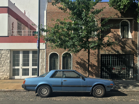 Side view of vintage blue car parked in the street in residential district in Buenos Aires, Argentina