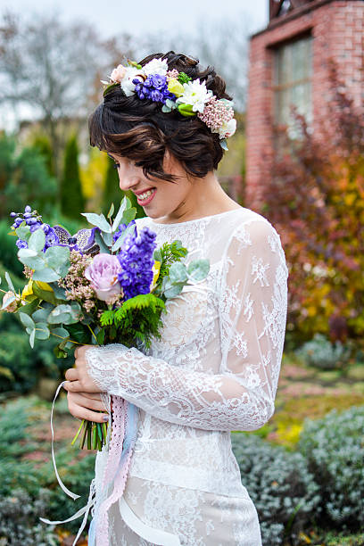 istock Beautiful brunette bride holding bouquet in hands and emotionally posing 636495356