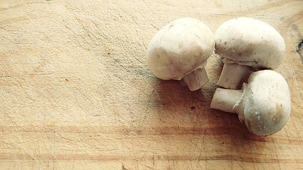 champignons liegen an einem alten holztisch - horrizontal stock-fotos und bilder