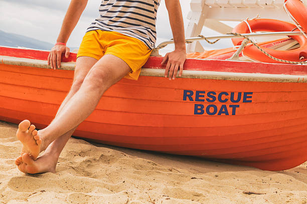 Lifeguard posing with his boat on the beach.