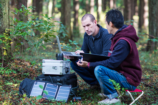 Two environmentalists or scientists monitor the forest with a solar powered field laboratory