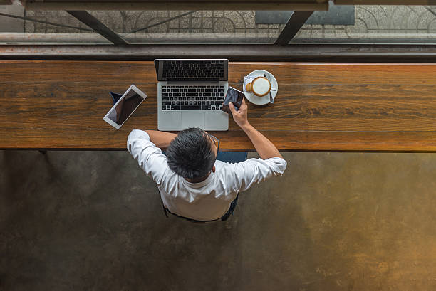 istock Businessman using laptop with smartphone and tablet beside cappuccino 636519416