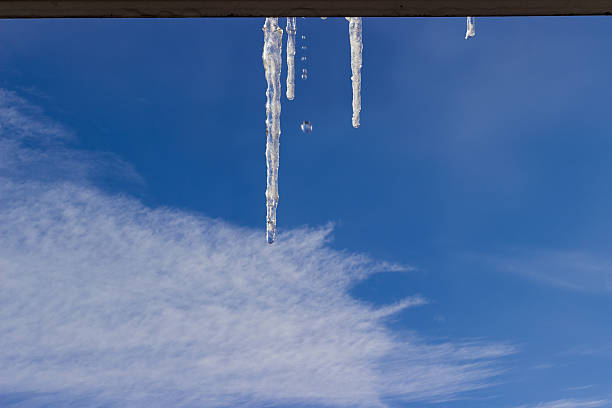 istock Several icicles with falling water drops on background of sky 636520934