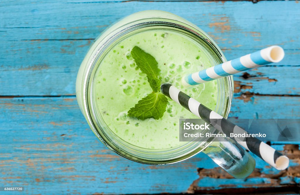 Refreshing green smoothie or milkshake in mason jar Refreshing Summer green smoothie or milkshake with mint, yogurt and kiwi. in mason jar, on blue wooden table, copy space, top view Milkshake Stock Photo