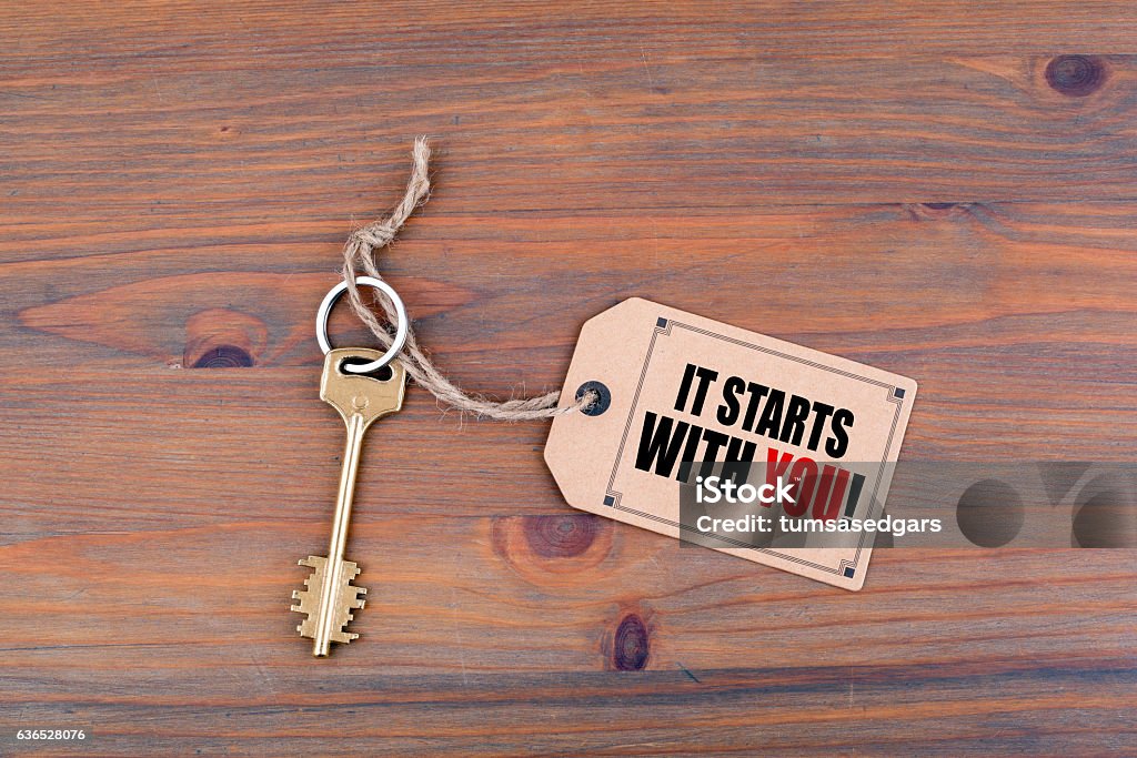 It Starts With You Key and a note on a wooden table with text - It Starts With You Individuality Stock Photo