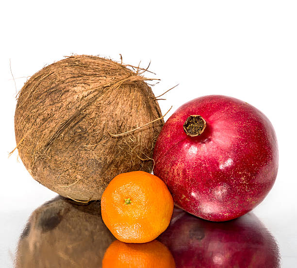 istock Coconut, pomegranate and tangerine on reflective background. 636531376