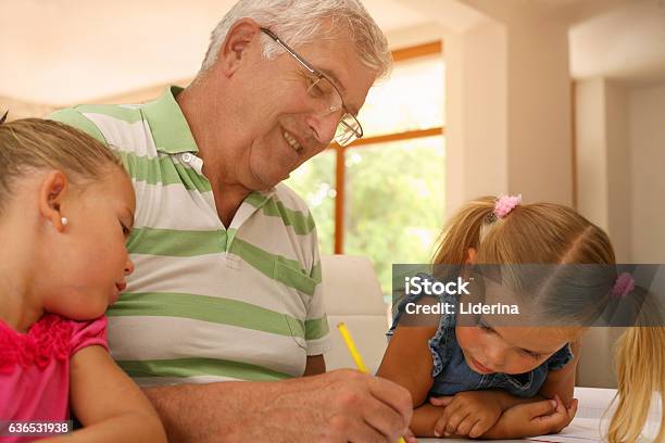 Grandfather Working Homework With Granddaughters Stock Photo - Download Image Now - Adult, Back to School, Blond Hair