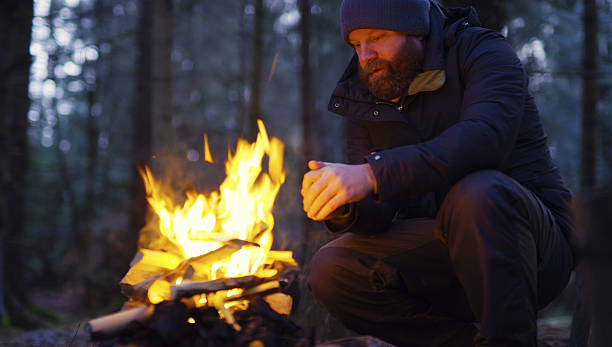 istock Man warms himself at camp fire in the forest 636532088