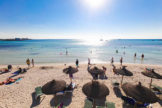 Es Trenc, Spain- October 3, 2016: The famous beach of Es Trenc on Mallorca, Spain. Lots of tourists are passing by and are lying under the parasols to get shelter of the hot sun.