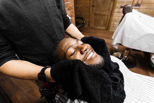After shaving Barber wiping his client face with towel after shaving black barber stock pictures, royalty-free photos & images
