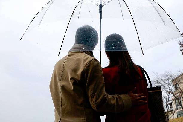 Siblings holding an umbrella watching the sea in rain