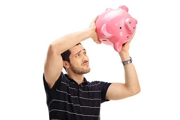 Photo of Worried guy shaking a piggybank