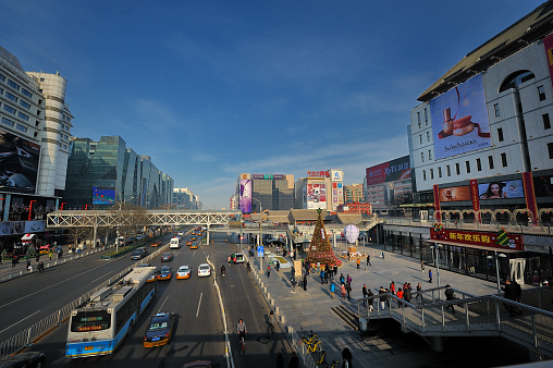 Beijing, China - December 16, 2016: The famous Xidan Commercial Street in Beijing, at the end of the year, there is a Christmas tree in the distance, pedestrians walking through the shops.