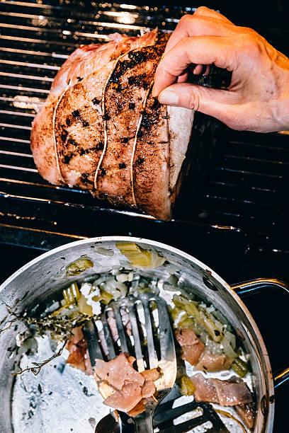 istock Human hand putting cloves into glazed ham 636541818