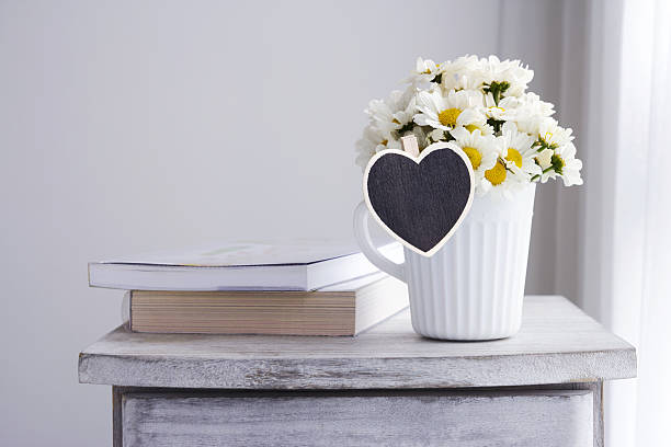 istock Fresh daisy flowers in white cup with blank wood heart 636546896