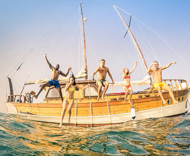 istock Young multiracial happy friends jumping from sailing party boat 636554178