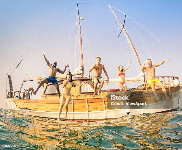 Young Multiracial Happy Friends Jumping From Sailing Party Boat Stock Photo - Download Image Now