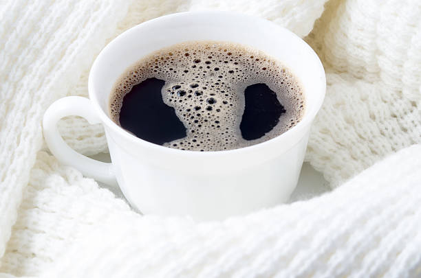 istock White cup of coffee surrounded by a white woolen scarf 636556624