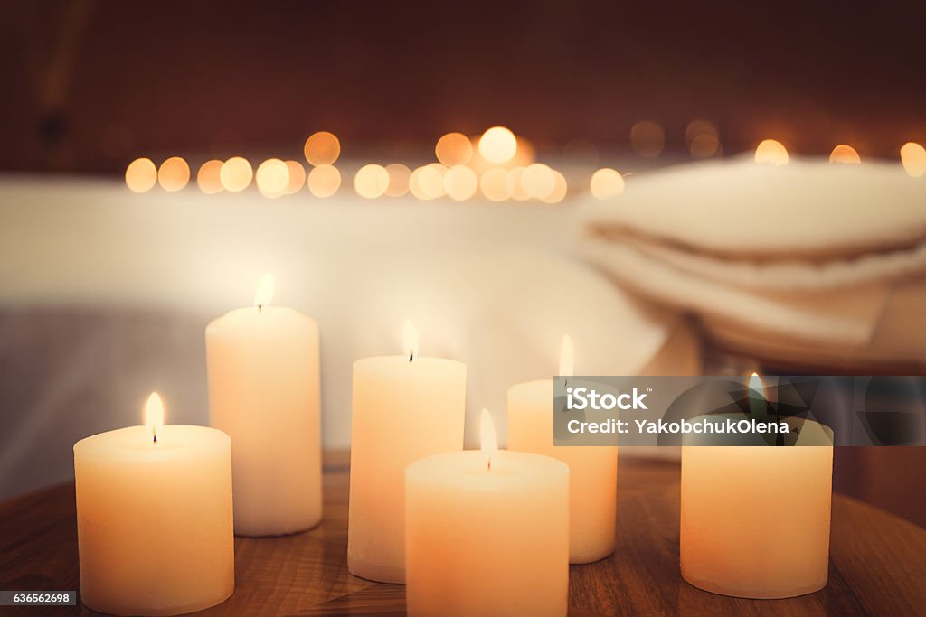 Harmony and luxury at beauty salon Close up of candles fire on small table. Bed for massage on background Candle Stock Photo