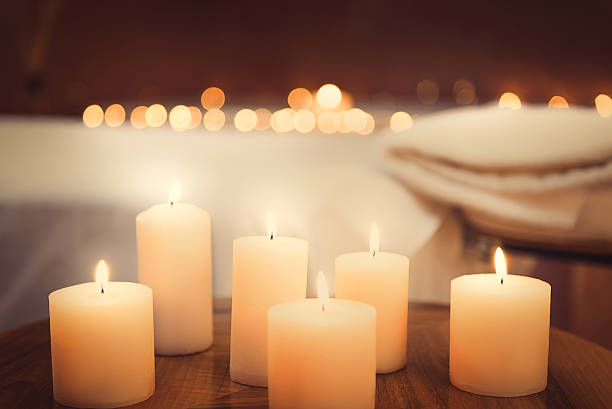 Harmony and luxury at beauty salon Close up of candles fire on small table. Bed for massage on background spa room stock pictures, royalty-free photos & images