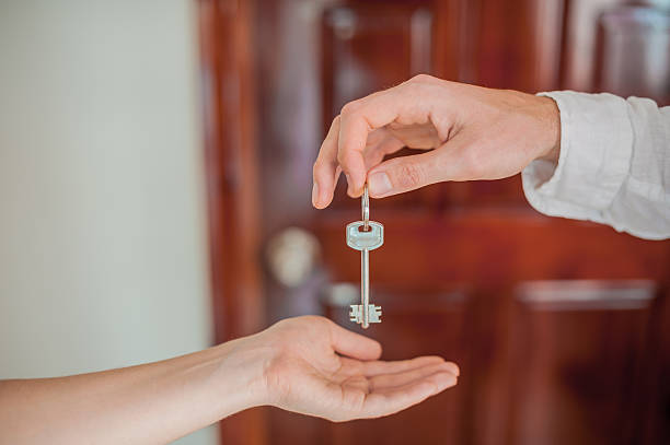 istock Man's hand gives a key female  on  background 636564474