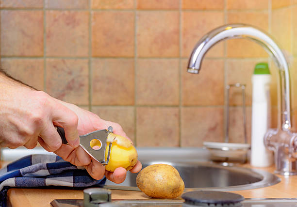 istock Peeling a potato with peeler in  kitchen 636569692