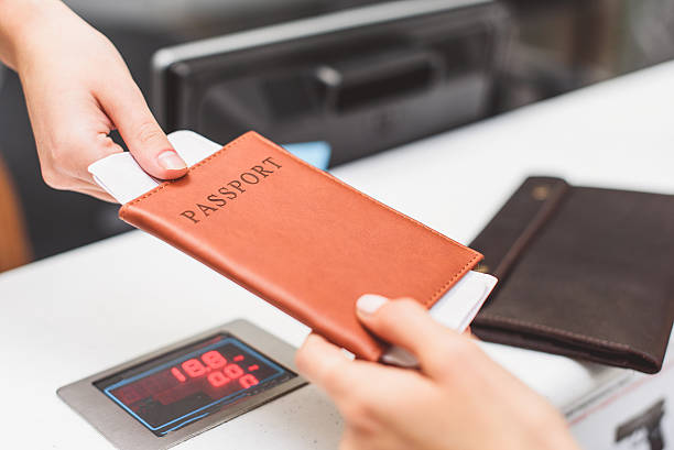 young woman giving boarding pass to inspector - airport airport check in counter arrival departure board checkout counter imagens e fotografias de stock