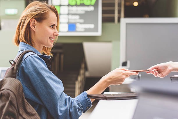 happy girl handing over passport in airport - airport arrival departure board airport check in counter airplane imagens e fotografias de stock