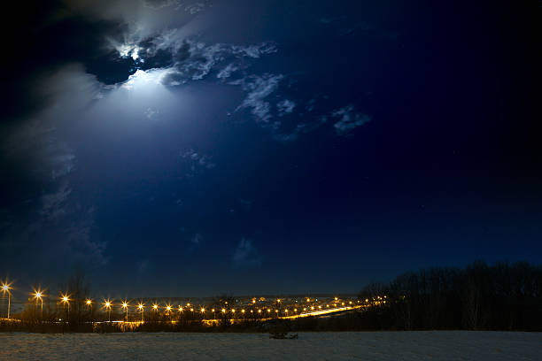 istock Moon with clouds in  night sky. Car highway lit lanterns. 636569988