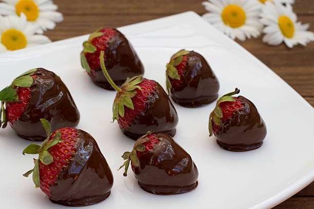 istock Strawberries dipped in chocolate on a white square plate. Wooden 636572912